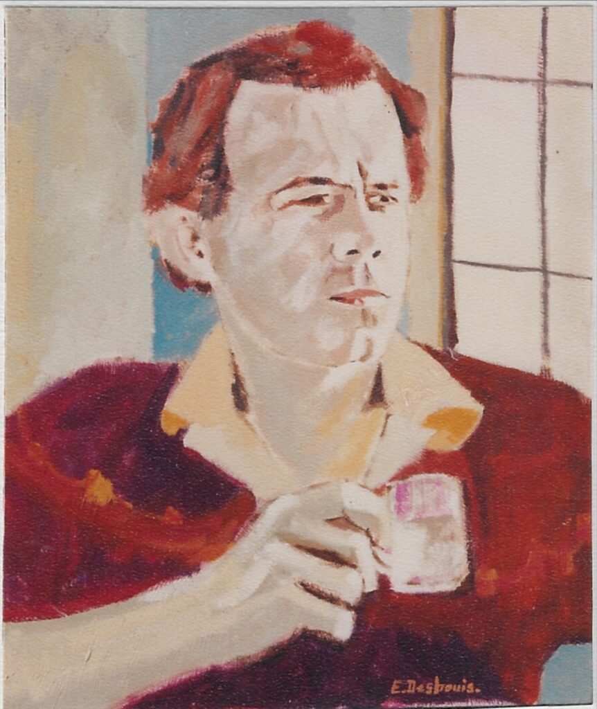 Buste de l’artiste col de chemise crème sur pull bordeaux, une tasse blanche dans la mais droite, regard lointain, fenêtre sur la droite.