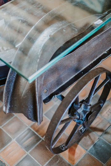 Détail de la table basse IPN en acier patiné sur roues en fer avec plateau en verre